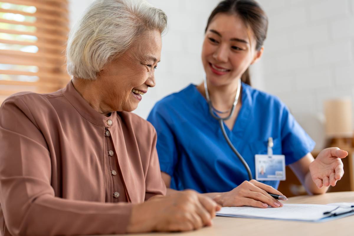 Asian young caregiver nurse examine senior woman patient at home. Attractive specialist carer women support, give advise and consult with older elderly mature grandmother in living room in house.