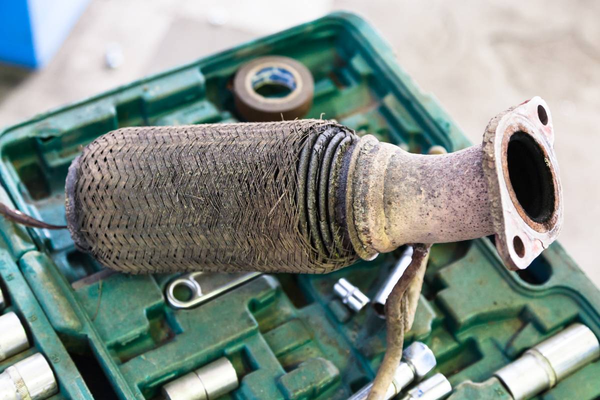 repairing of corrugation muffler of exhaust system in car workshop - old burnt corrugation muffler on set of tools