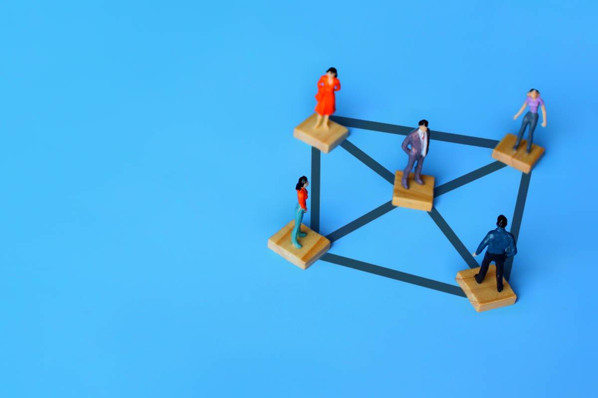 Selective focus image of connected miniature people on wooden cubes. Connection, networking, and social network service concept. Copy space for text