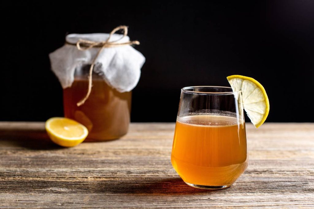 Raw fermented homemade alcoholic or non alcogolic kombucha superfood. Ice tea with healthy natural probiotic in glass with lemon slice on wooden background (Raw fermented homemade alcoholic or non alcogolic kombucha superfood. Ice tea with healthy nat