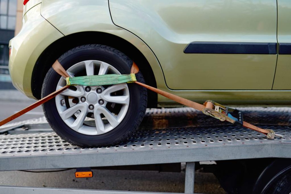 Car wheel fixing tow truck mechanism with belt in platform to protect from moving. Cropped shot