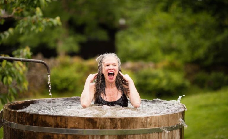 Mature woman in fresh ice bath tub at eco retreat